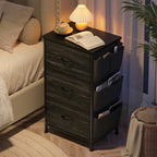 Black fabric drawer nightstand at night holding an open book under a warm lamp