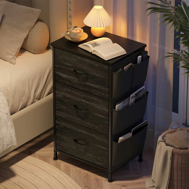Black fabric drawer nightstand at night holding an open book under a warm lamp