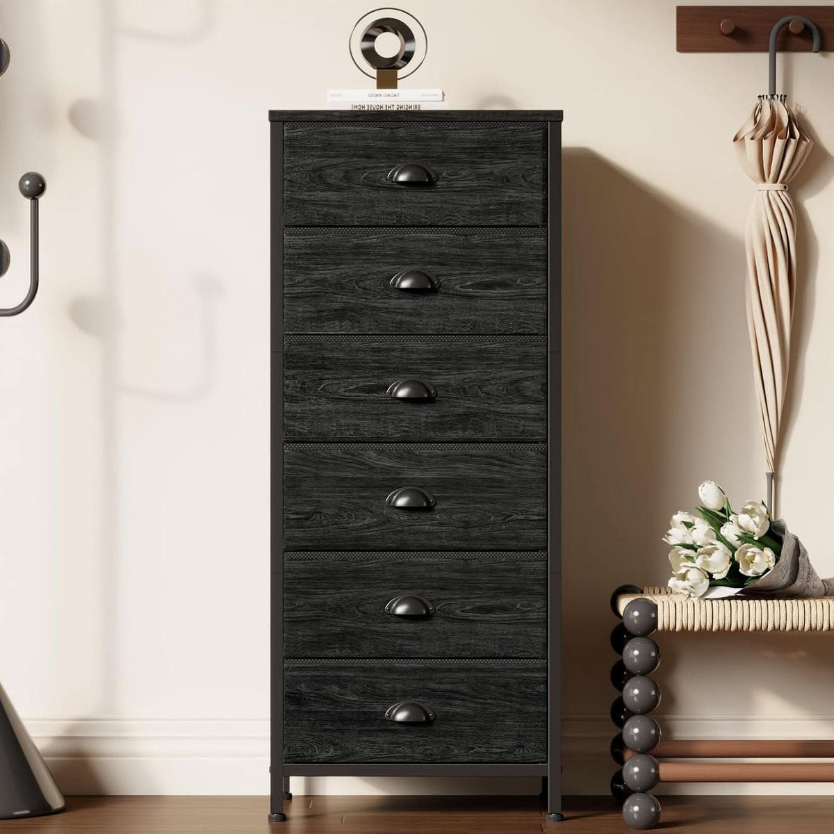 The six drawer tower in a hallway beside a coat hook with an umbrella and decor