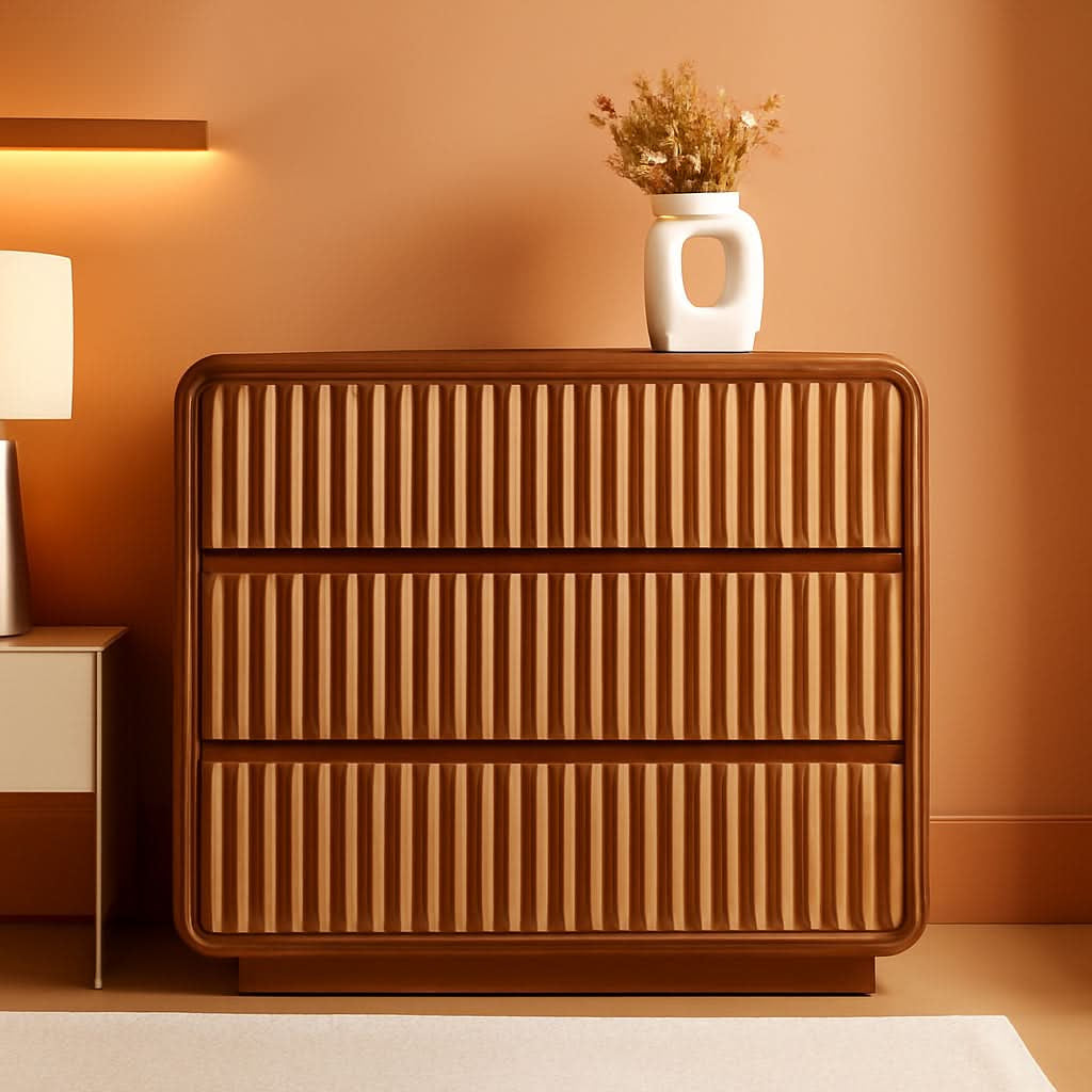 Walnut fluted three drawer dresser against a warm orange wall with a vase on top