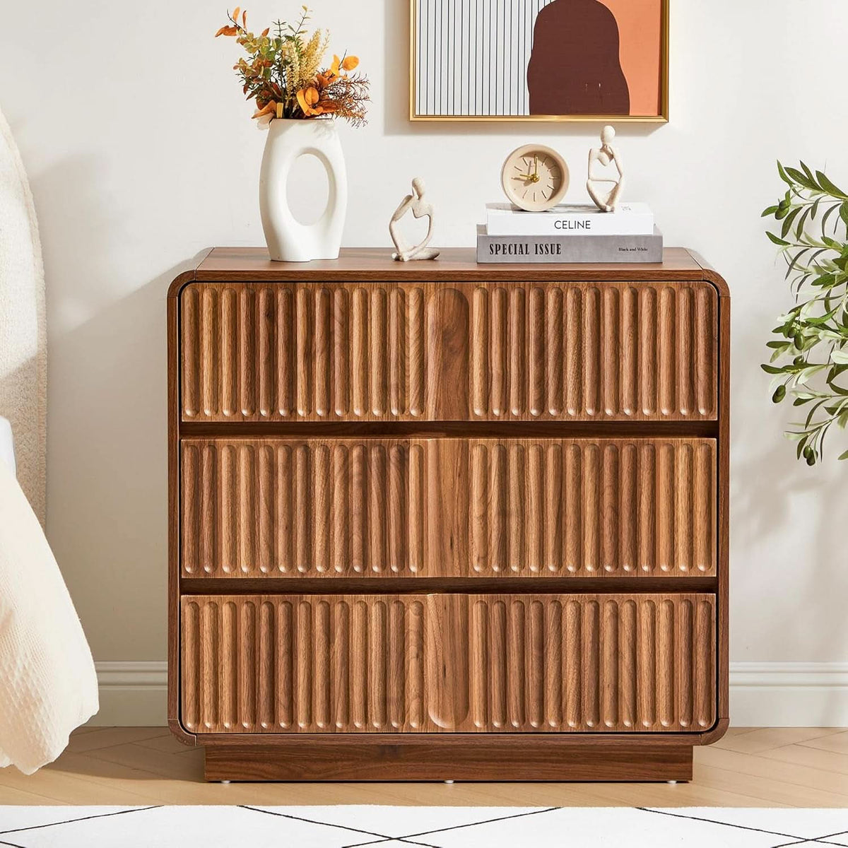 The fluted walnut chest in a bedroom with books, a clock and dried flowers on top