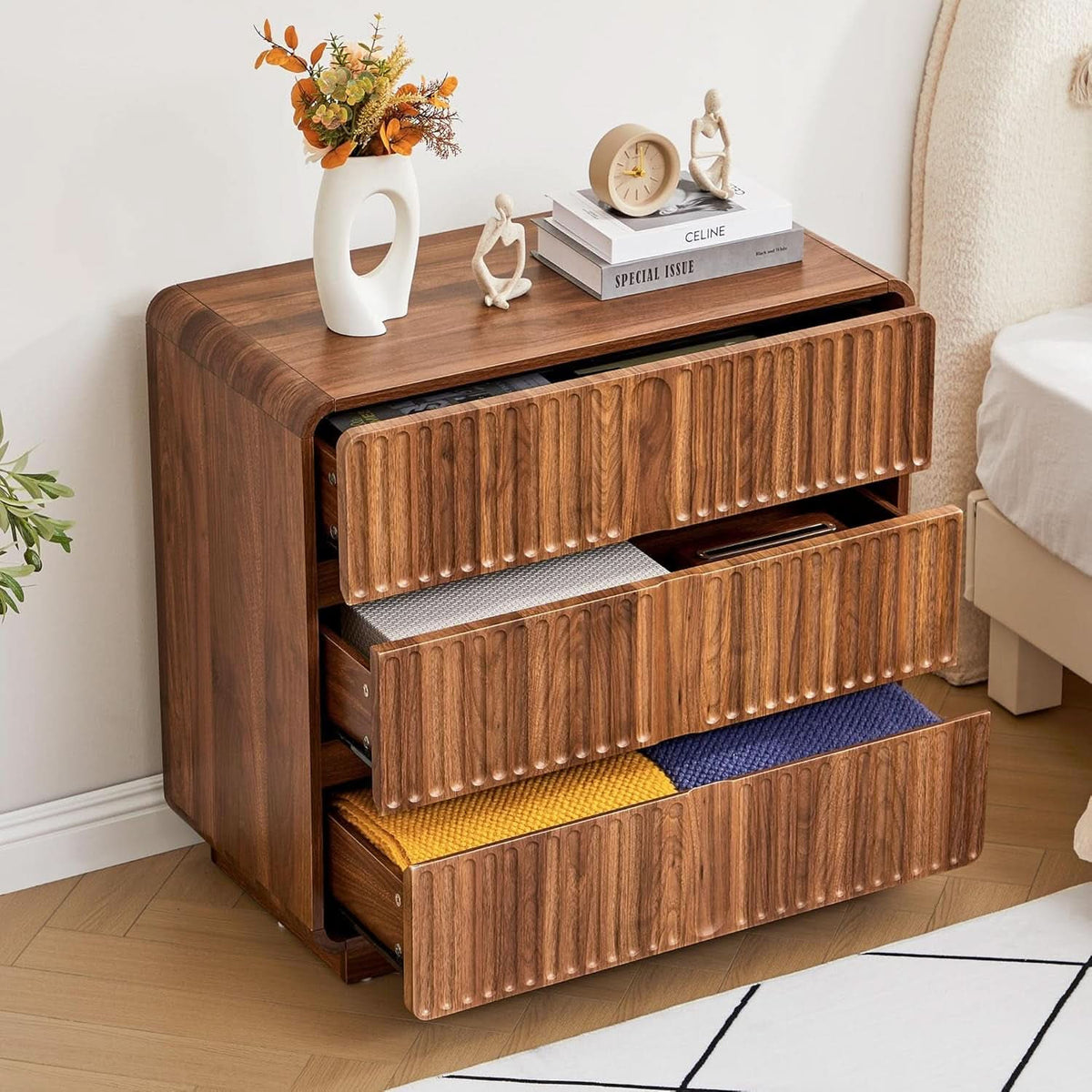 All three drawers open showing folded clothes inside the walnut chest