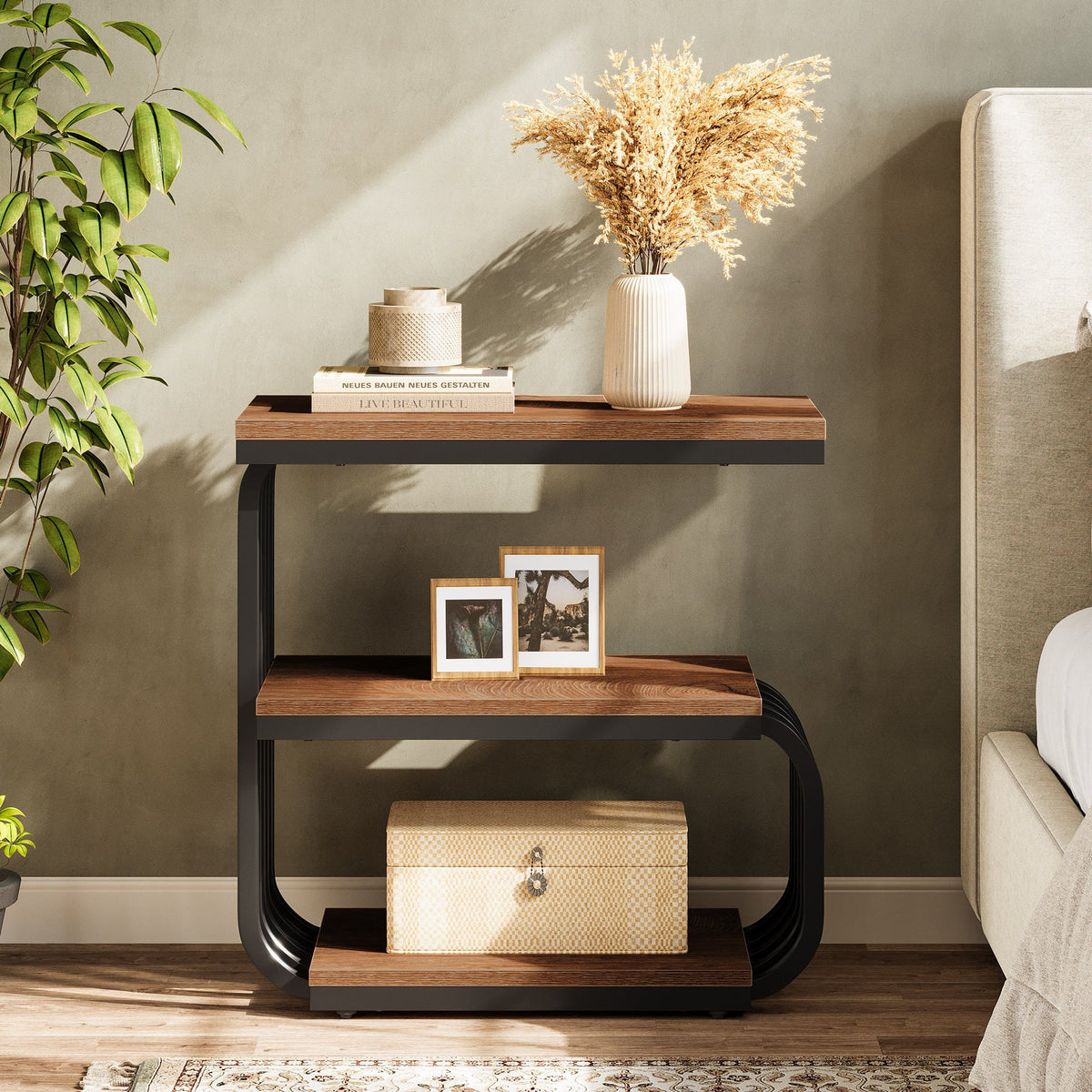 Brown three tier side table beside a sofa holding a vase and frames