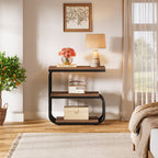 Three tier bedside table with a lamp beside a bed and a plant