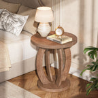 Round bedside table with lamp and books by a cream headboard