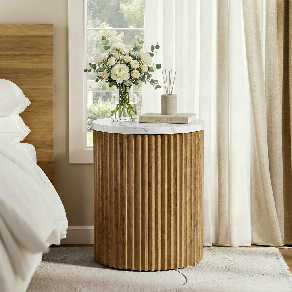 Drum pedestal bedside table with flowers by a cream bed