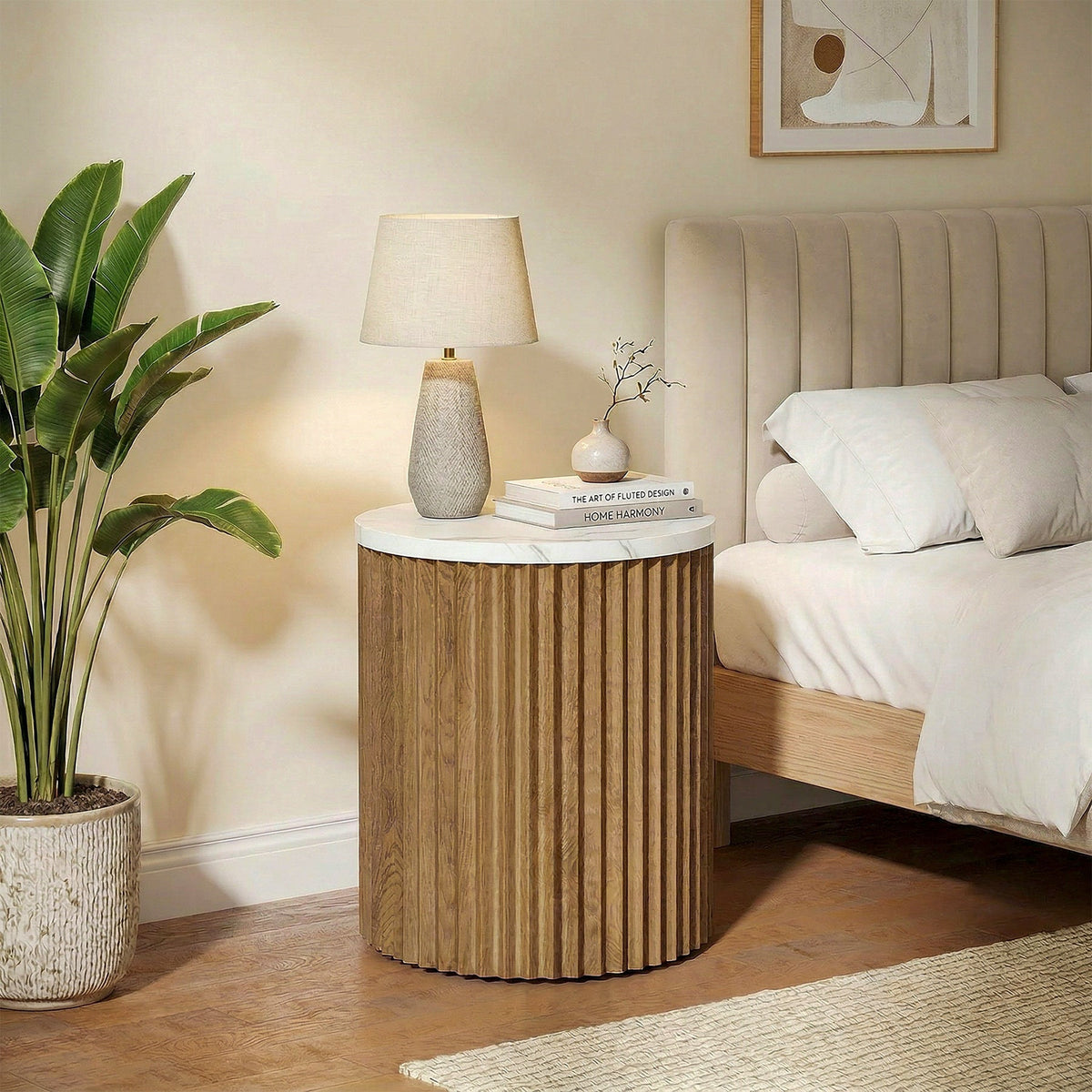 Ribbed base nightstand with lamp beside an upholstered bed