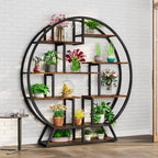 The circular plant stand styled with flowering plants against a white brick wall