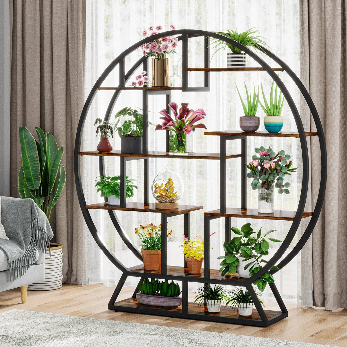 Round plant stand filled with plants standing in front of a curtained window