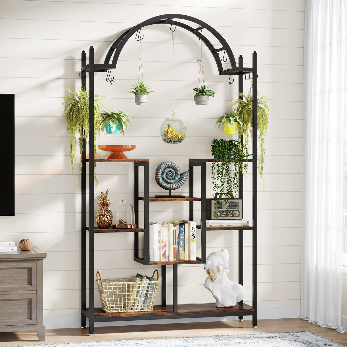 Arched plant stand against a white panelled wall with books and plants