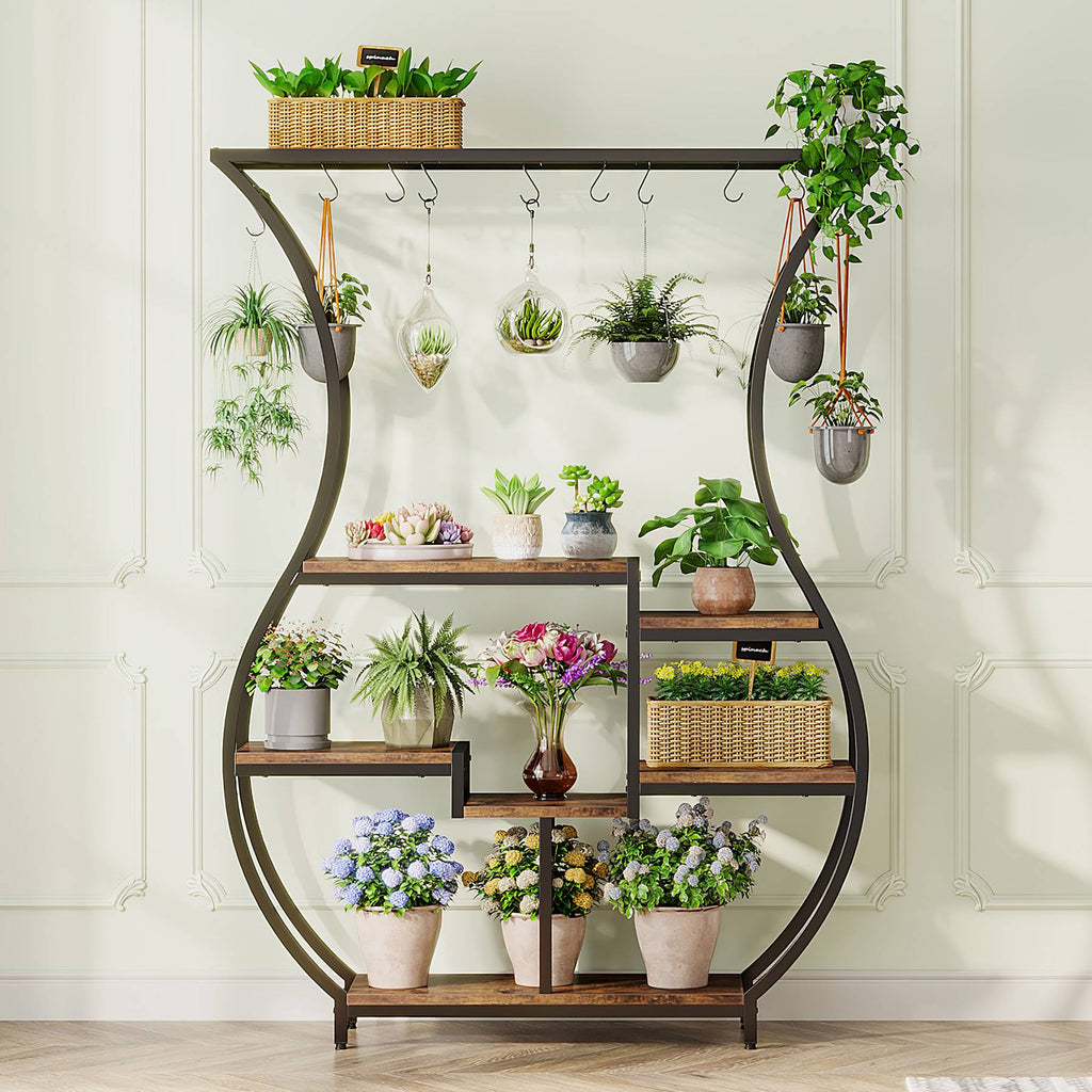 Six tier plant stand against a white wall holding flowering plants
