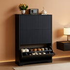 Black fluted shoe cabinet 30.9 x 9.4 x 47.8 in in an entryway with the bottom flip drawer open showing two rows of shoes, a plant and a clock on the top surface