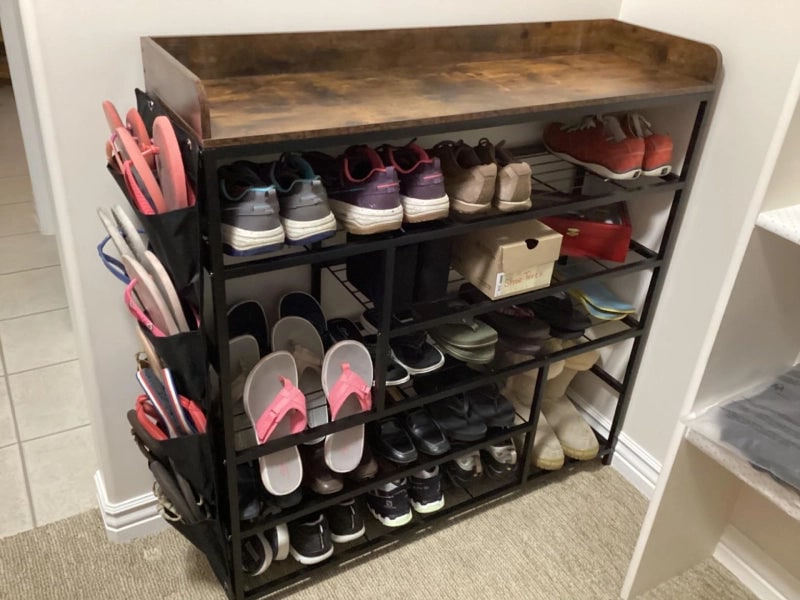 Six tier shoe rack with a wood top in a home entryway, filled with everyday shoes and slippers