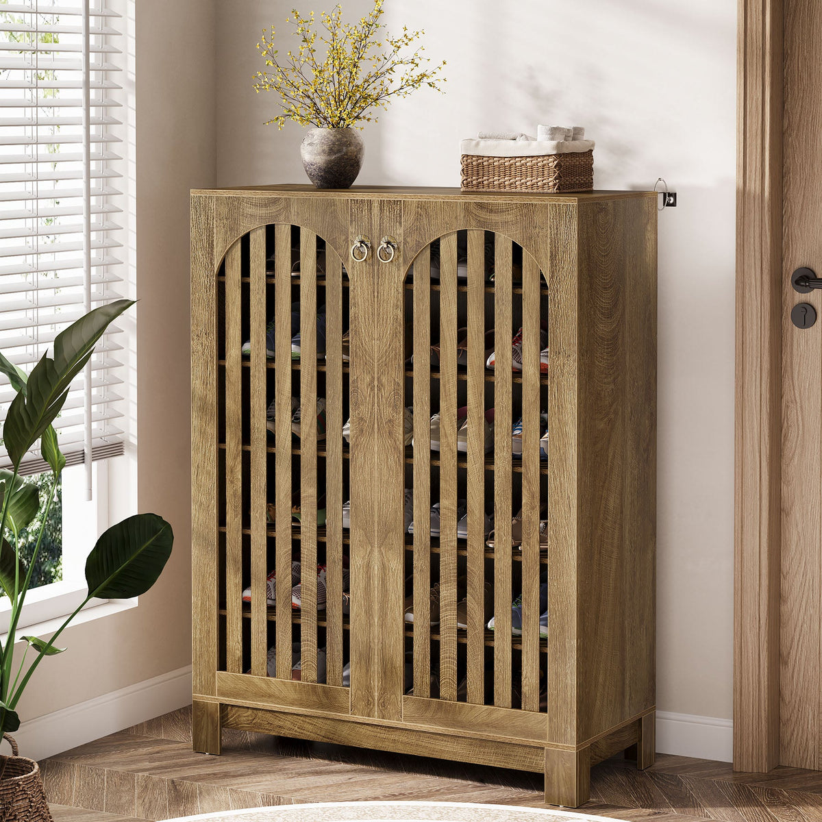 Louvered shoe cabinet beside a door with flowers on top