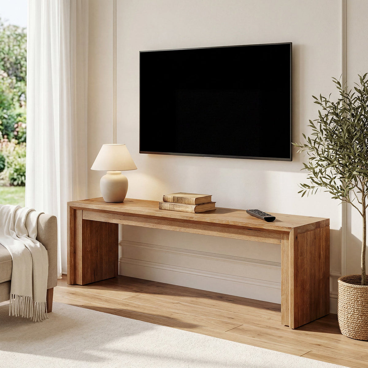 Wood TV stand under a wall mounted TV with a table lamp