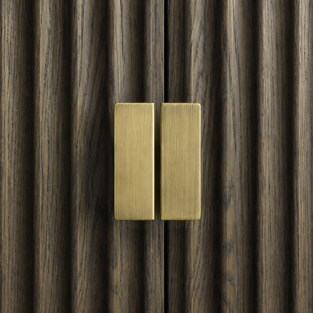 Close-up of brushed brass handles on fluted Grey Oak doors